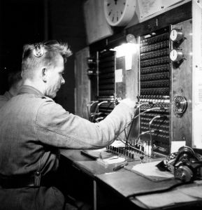Riihimäen varuskunnan käsivälitteinen puhelinkeskus 1950-luvun lopulla. Varuskuntakeskusten puhelunvälittäjiksi koulutettiin myös varusmiehiä. 